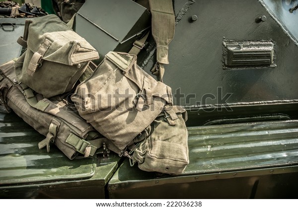 Military\
canvas kit bags hanging over an armoured\
car.