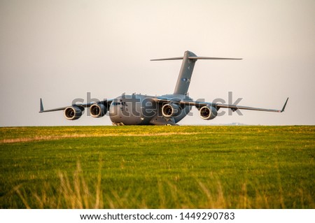 Military cargo plane parked on grassy meadow