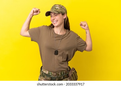 Military caucasian woman with dog tag isolated on yellow background celebrating a victory