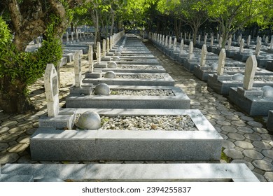 Military cemetery in Indonesia with white headstones rows for soldiers and war helmets. Hero Cemetery Park (Taman Makam Pahlawan) at Memorial day, November 10th
