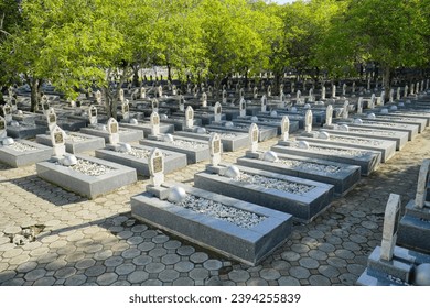 Military cemetery in Indonesia with white headstones rows for soldiers and war helmets. Hero Cemetery Park (Taman Makam Pahlawan) at Memorial day, November 10th