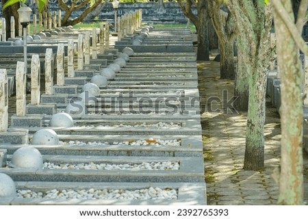 Military cemetery in Indonesia with white headstones rows for soldiers and war helmets. Hero Cemetery Park (Taman Makam Pahlawan) at Memorial day, November 10th