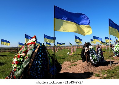 Military cemetery in Ukraine. Soldiers of Ukrainian army who died in Russian war against Ukraine are buried here. National flag of Ukraine flutters over monuments. Dnipro, Ukraine, 2022-05-07 