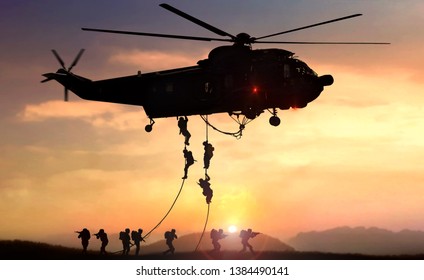 Military commando helicopter drops in silhouette during sunset