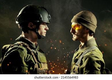 Military conflict. Two brave soldiers in Protective Combat Uniform stand face-to-face looking seriously at each other. Dark background with smoke and sparks of fire. War concept. 