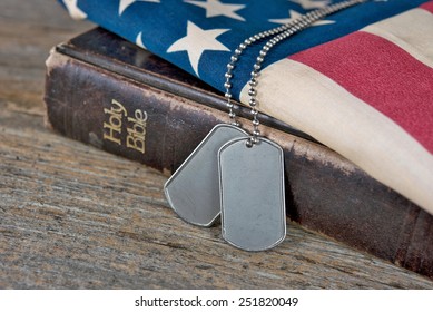 military dog tags on American flag with old Holy Bible on rustic wood - Powered by Shutterstock