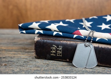 military dog tags on American flag and worn Holy Bible - Powered by Shutterstock