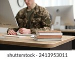 Military education. Student in soldier uniform learning at wooden table indoors, selective focus