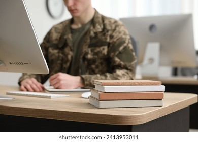 Military education. Student in soldier uniform learning at wooden table indoors, selective focus - Powered by Shutterstock