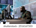 Military expert in an advanced operations center oversees satellite intelligence, managing surveillance systems on computer. Interpreting data to ensure national defense and strategic decisions.