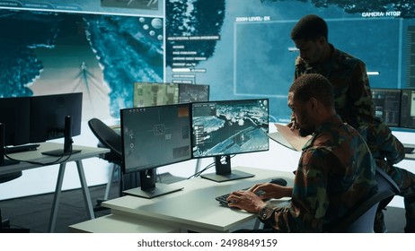 Military experts in mission control center use modern technology on computer and big screen, analyzing satellite footage. Specialist tracking potential threats for intelligence operations. Camera B. - Powered by Shutterstock