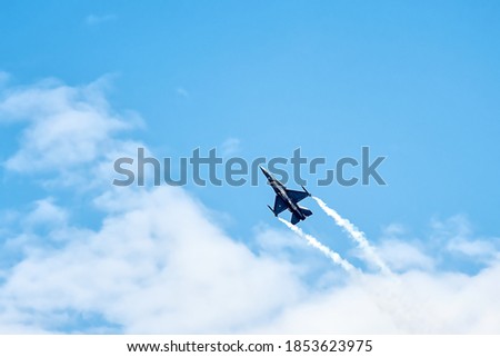 Military F16 fighter jet flying through the blue sky.