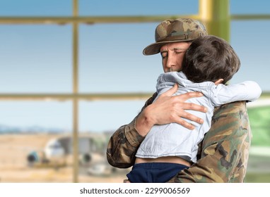 Military father hugs his son when they are reunited after a mission with a blue sky in the background and copy space. - Powered by Shutterstock