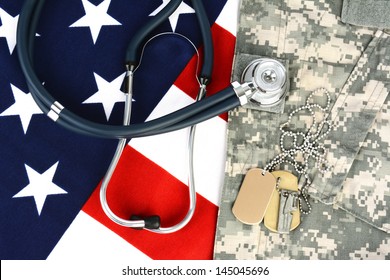 Military Fatigues And Dog Tags On An American Flag With A Stethoscope To Illustrate Health Care In The Armed Services. Horizontal Format, Fills The Frame.