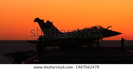 military fighter jet during sunset at aircraft carrier, with silhouette