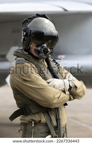 Military Fighter Pilot with helmet, visor and oxygen mask in flying suit with fighter jet. 