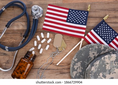 Military Health Care Concept. Camo Hat, Dog Tags, Stethoscope, Pills, And American Flags On A Wood Background. 