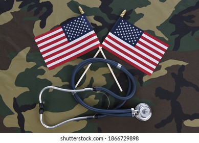 Military Health Care Concept. Camouflage Background With Stethoscope And Two Crossed American Flags.