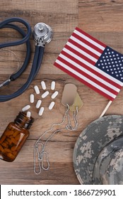 Military Health Care Concept. Dog Tags, Stethoscope, Pills, Camouflage Hat And American Flag On A Wood Background. 