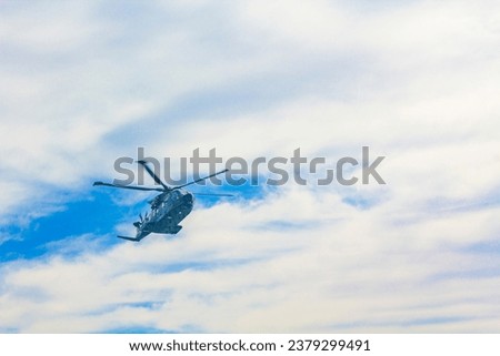 Military helicopter aerial lift truck flies over the Ferry and the sea in Hirtshals Jutland Denmark.