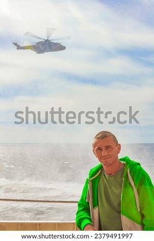 Military helicopter aerial lift truck flies over the Ferry a tourist and the sea in Hirtshals Jutland Denmark.
