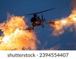 Military helicopter in flight firing off flare decoys at night.