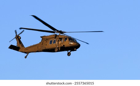 A military helicopter maneuvers through the clear blue sky, showcasing its agility and design features. - Powered by Shutterstock