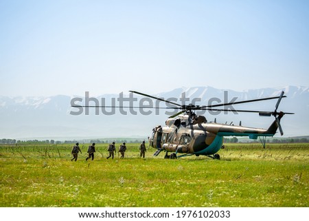 Military helicopter with soldiers. Armed conflict in Afghanistan, fighting. Soldiers in camouflage clothing goes to a military helicopter. Air armament, parachutist.