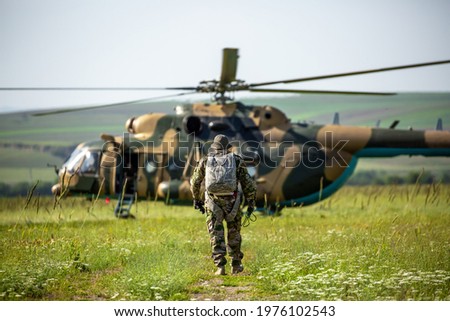 Military helicopter with soldiers. Armed conflict between Israel and Palestine, military action. A soldier in camouflage clothing walks towards a military helicopter. Air armament, parachutist.