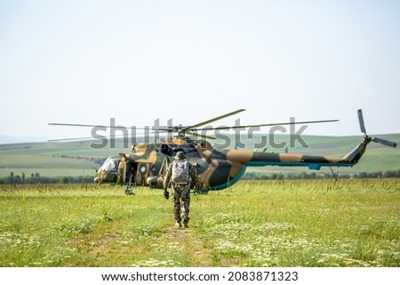 Military helicopter with soldiers. Armed conflict between Israel and Palestine, military action. A soldier in camouflage clothing goes to a military helicopter. Air armament, parachutist.