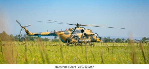 A military helicopter stands on the ground in a field with its propellers on. Armed conflict. Defense Army. Military aircraft on mission. - Powered by Shutterstock