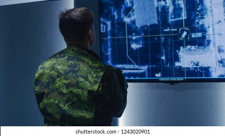 Military Man / Army Officer Watches Satellite Surveillance Footage / Car Tracking Of The Target On Wall TV Screen. Secret Military Spying Operation In The Surveillance Center / System Control Room.