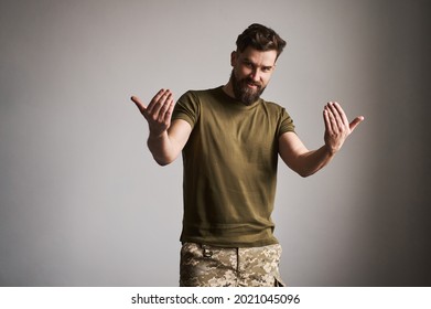 Military man calling for a fight and challenging someone. Strong and handsome soldier in uniform on gray background.