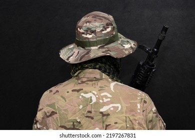 A Military Man In Camouflage And A Panama Hat With A Rifle In His Hands On A Black Background. Concept: Military Operations, Soldier Of Fortune, Army Offensive.