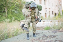 A Military Man Carries His Wounded Partner During Combat Operations. A Soldier's Friend Saves His Comrade. Patriotism, Loyalty, Bravery. An Accident During The War.