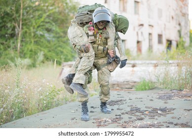 A military man carries his wounded partner during combat operations. A soldier's friend saves his comrade. Patriotism, loyalty, bravery. An accident during the war.