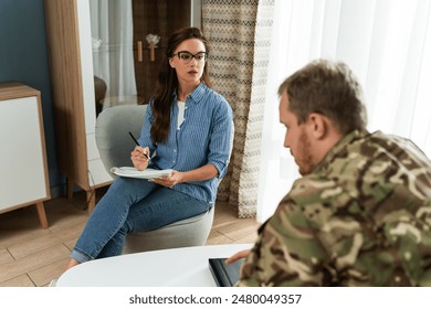 Military man in counseling for trauma therapy due to military war and talking army mental health support. Consultation, depression and sad man with help for psychology problem on a sofa  - Powered by Shutterstock