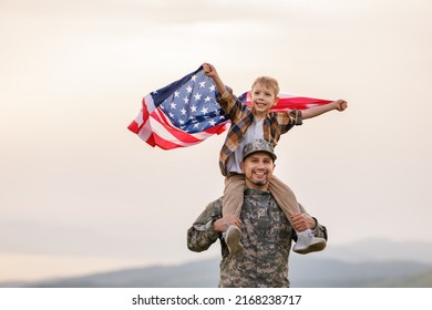 Military man father carrying happy little son with american flag on shoulders and enjoying amazing summer nature view on sunny day on July 4th, happy male soldier dad reunited with son after US army - Powered by Shutterstock