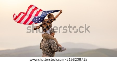 Military man father carrying happy little son with american flag on shoulders and enjoying amazing summer nature view on sunny day on July 4th, happy male soldier dad reunited with son after US army