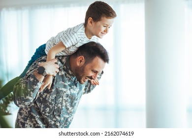 Military Man Father Hugs Son. Portrait Of Happy American Family. Young Soldier Just Arrived Home And He Is So Happy To See His Son. My Hero Is Back Home