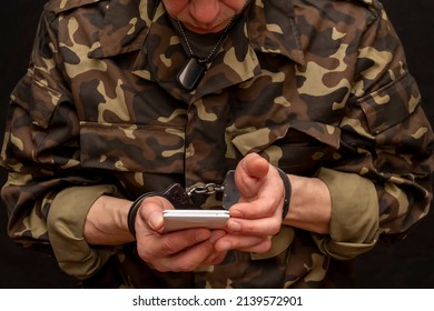 A Military Man In Handcuffs Makes A Phone Call On A Dark Background, Selective Focus. Concept: Prisoner Of War Talking On The Phone, Prisoner Exchange.