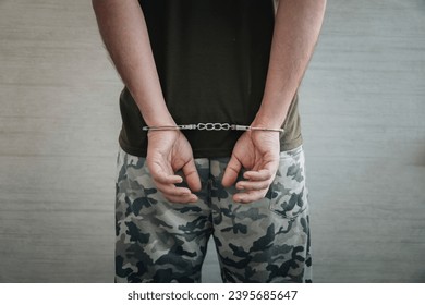 A military man in handcuffs on a dark background, selective focus. Concept: war criminal, prisoner of war, tribunal for deserters, traitor to the Motherland. - Powered by Shutterstock