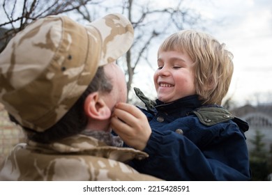 Military Man Standing With His Back Holds A Happy Child In His Arms. The Long-awaited Joyful Meeting Of Father And Son After Military Service