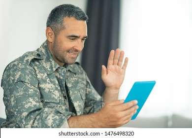 Military Man Waving. Dark-haired Military Man Waving While Having Video Chat With Family On Tablet