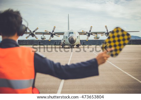 Military men are signaling a C130 military aircraft, propeller aircraft.

