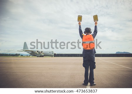 Military men are signaling a C130 military aircraft, propeller aircraft.

