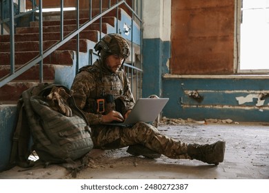 Military mission. Soldier in uniform using laptop inside abandoned building - Powered by Shutterstock