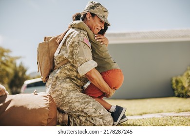 Military Mom Embracing Her Son After Returning Home From The Army. Courageous Female Soldier Having An Emotional Reunion With Her Young Child After Military Deployment.