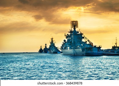 Military Navy Ships In A Sea Bay At Sunset Time