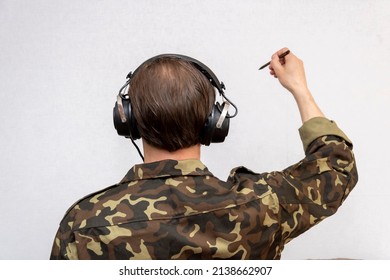 A Military Officer With Headphones Draws With A Pencil On A White Background, Selectively Focuses. Concept: Military Cartographer, Secret Spy, Special Operations Map, Army Headquarters.